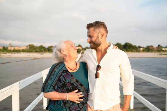 Man with senior mother embracing on pier