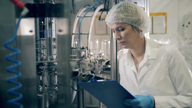 Dairy plant unit and a lady specialist is taking notes in it