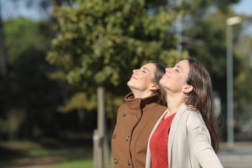 Two relaxed women breathing fresh air in winter in a park