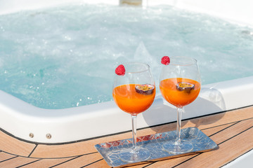 Closeup shot of two glasses of a cocktail with maracuya near the jacuzzi