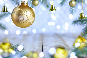 Christmas bokeh background with fir branches, bell and gold ornate ball. Copy space, soft focus