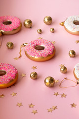 Christmas toys in the form of donuts on a pink background with gold decor, selective focus, side view. Creative food minimalism