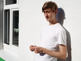 Portrait of a young guy of model appearance standing near a white wall