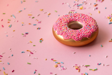 Donut and colored sprinkles on a pink background. Christmas toys in the form of donuts.  Creative food minimalism, side view with copy space