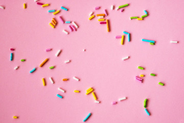 Colorful sprinkles on a pink background, top view with copy space