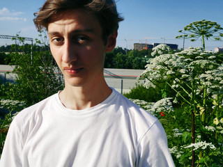 Portrait of a young guy model looks among the green plants