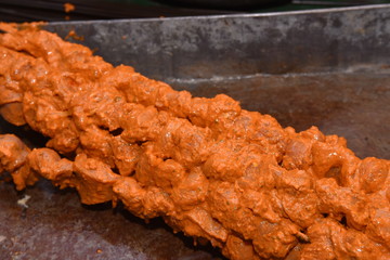 Chef preparing fresh hot grilled chicken seekh kebabs barbecue on grid over charcoal