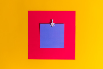 Blank blue square reminder memo note for writing ideas, things to do attached on a bright red and yellow background with christmas decorative pin. Festive planning, Gift list. Minimalistic concept.