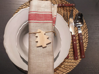 Mesa adornada para navidad y fin de año. Decoración navideña en colores tierra, platos, servilletas y mantel. Adonos de árbol, corazón y estrella de madera. Horizontal y vertical.