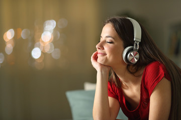 Relaxed woman listening to music at home in the night