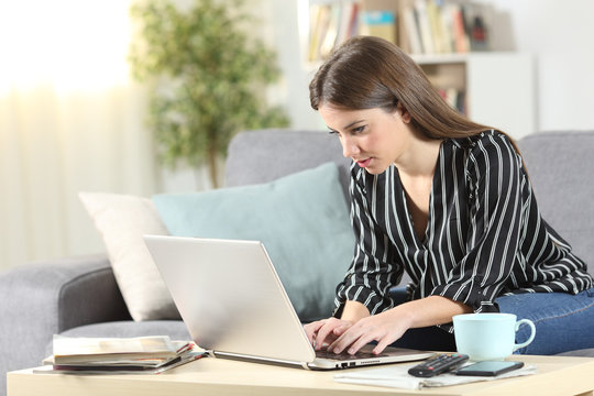 Woman using a laptop sitting on a couch at home