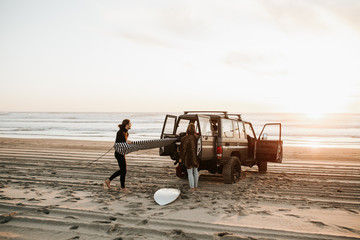 Man loading surfboard in car on beach