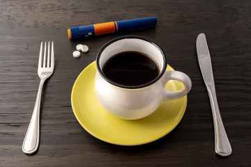 meal setting, fasting with coffee, diabetic medication and insulin syringe.
