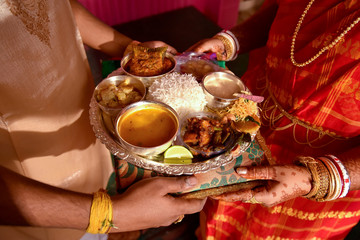 Newly married husband and wife exchanging Traditional Indian food Thali after marriage , A...