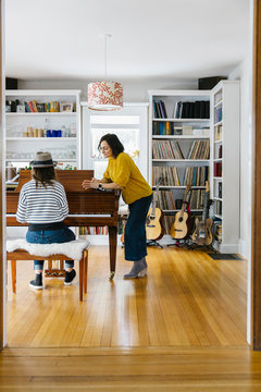 Mother Listening to Daughter play the piano at home music Studio