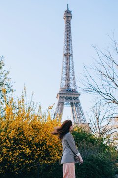 Unrecognizable red head woman posing by the Eiffel tower in yellow bloom