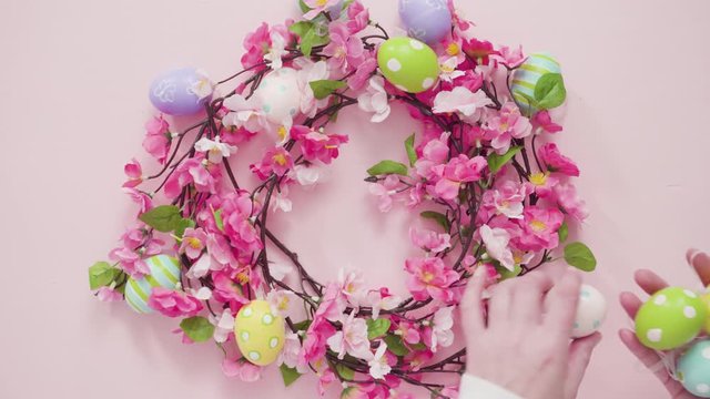 Easter eggs and pink flowers on a pink background.