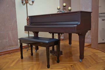 Old wooden piano keys on wooden musical instrument in front view . Big brown wooden piano close up in room .