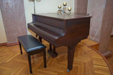 Old wooden piano keys on wooden musical instrument in front view . Big brown wooden piano close up in room .