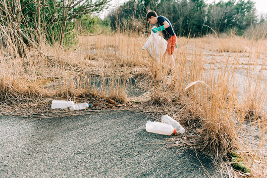 boy picking up trash for earth day, trash in foreground