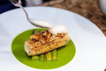 Closeup shot of grilled fish and fried asparagus in a green vegetarian sauce
