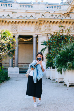 Young woman in beautiful place tacking picture of photographer with her phone