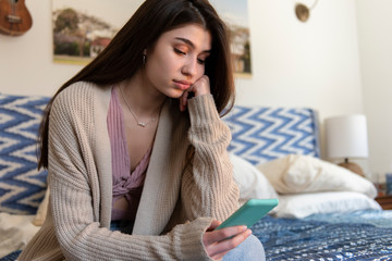 Sad teenager looking at her phone