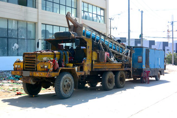 Old yellow drilling machine drags a trailer