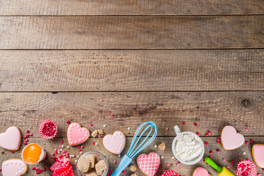 Valentine day cooking baking background. Utensils and ingredient for sweet Valentine cakes and heart shaped cookies, wooden background copy space