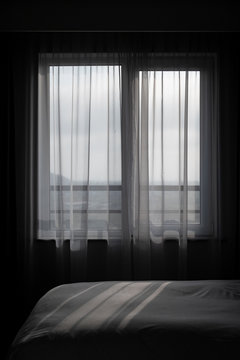 Shadow falls through a window onto a made bed