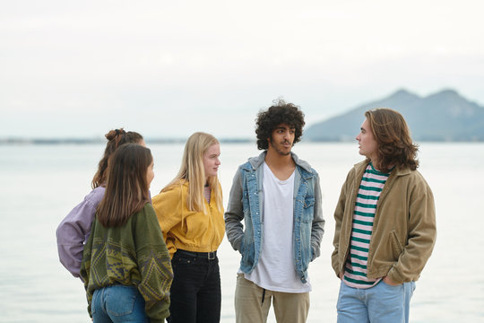 Five best friends talking, resting near lake.