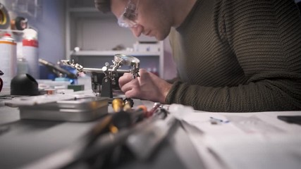 Electronics repairman master repairs smartphone in service center.