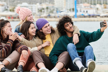 Young friends taking selfie on pier