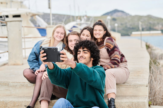 Young stylish friends taking selfie on seashore
