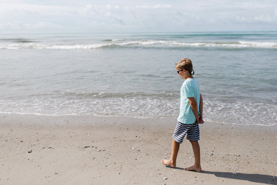 pre-teen boy walks on the beach