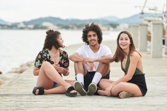 Joyful teen friends chilling on pier