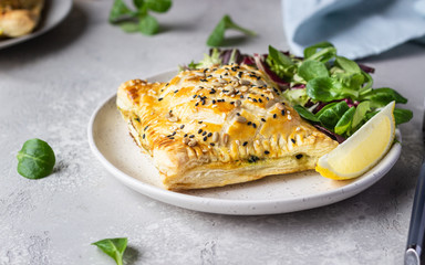 Puff pastry pie with salmon, spinach and ricotta cheese served with green lettuce leaves. Salmon Wellington in puff pastry.