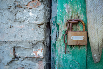Vintage padlock with a grungy wooden door and a rough brick wall with stucko fragment. Copy Space for text.