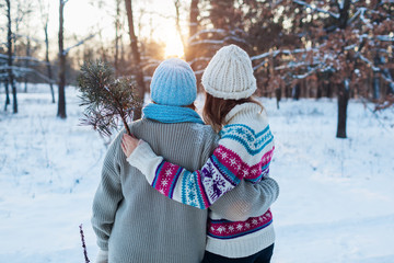 Winter walk. Mother and adult daughter admire snowy forest landscape. Family hugging, relaxing...
