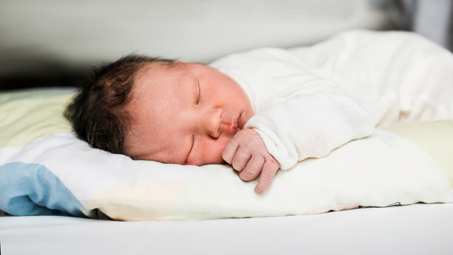 Newborn baby laying on a bed