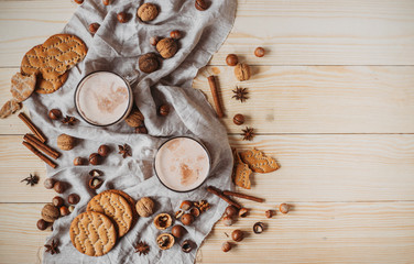 Hot cocoa with cookies, cinnamon sticks, anise, nuts on wooden background. Top view, copy space.