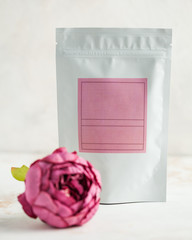 packaging for tea, coffee, solids with a pink label, in the foreground a pink peony flower