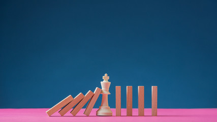 King chess figure standing in the middle of falling dominos