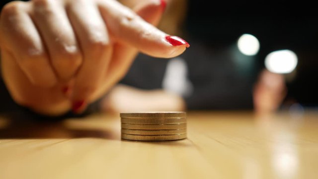 coins lie on the table and the girl&rsquo;s finger points to them