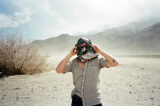 Male with shirt over face in windy desert