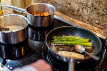 Closeup shot of fresh green asparagus being fried in a pot on a gas stove