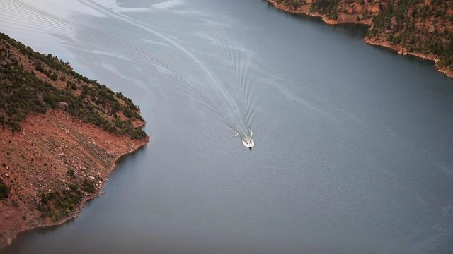 Canyon Rim high angle closeup view in Flaming Gorge Utah National Park with Green River at sunset and boat wakeboard fun turning around