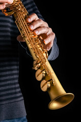 soprano saxophone in the hands of a guy on a black background