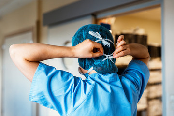 Back view of doctor covering her face with surgical mask