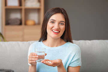 Young woman taking medicine at home